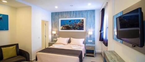 Habitación de hotel con cama, escritorio, televisor, sofá y un cuadro en la pared.