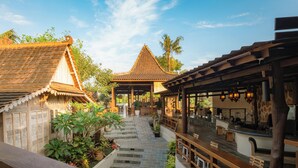 A traditional building with a tiled roof, a covered walkway, and wooden benches. - Artropeace Ubud Retreat & Villas (Ubud)