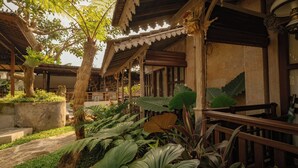A traditional building with a covered patio area, large plants, and a wooden railing. - Artropeace Ubud Retreat & Villas (Ubud)