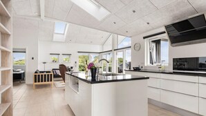 Une cuisine moderne dotée d’un îlot central, de grandes fenêtres et offrant une vue sur l’extérieur.