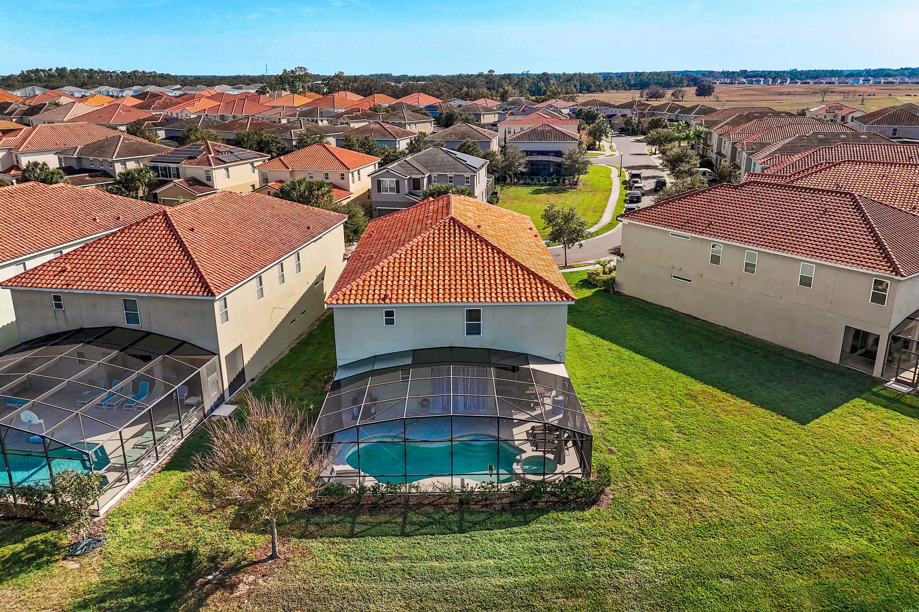 A residential area with houses featuring red-tiled roofs, a swimming pool, and a curved glass enclosure.