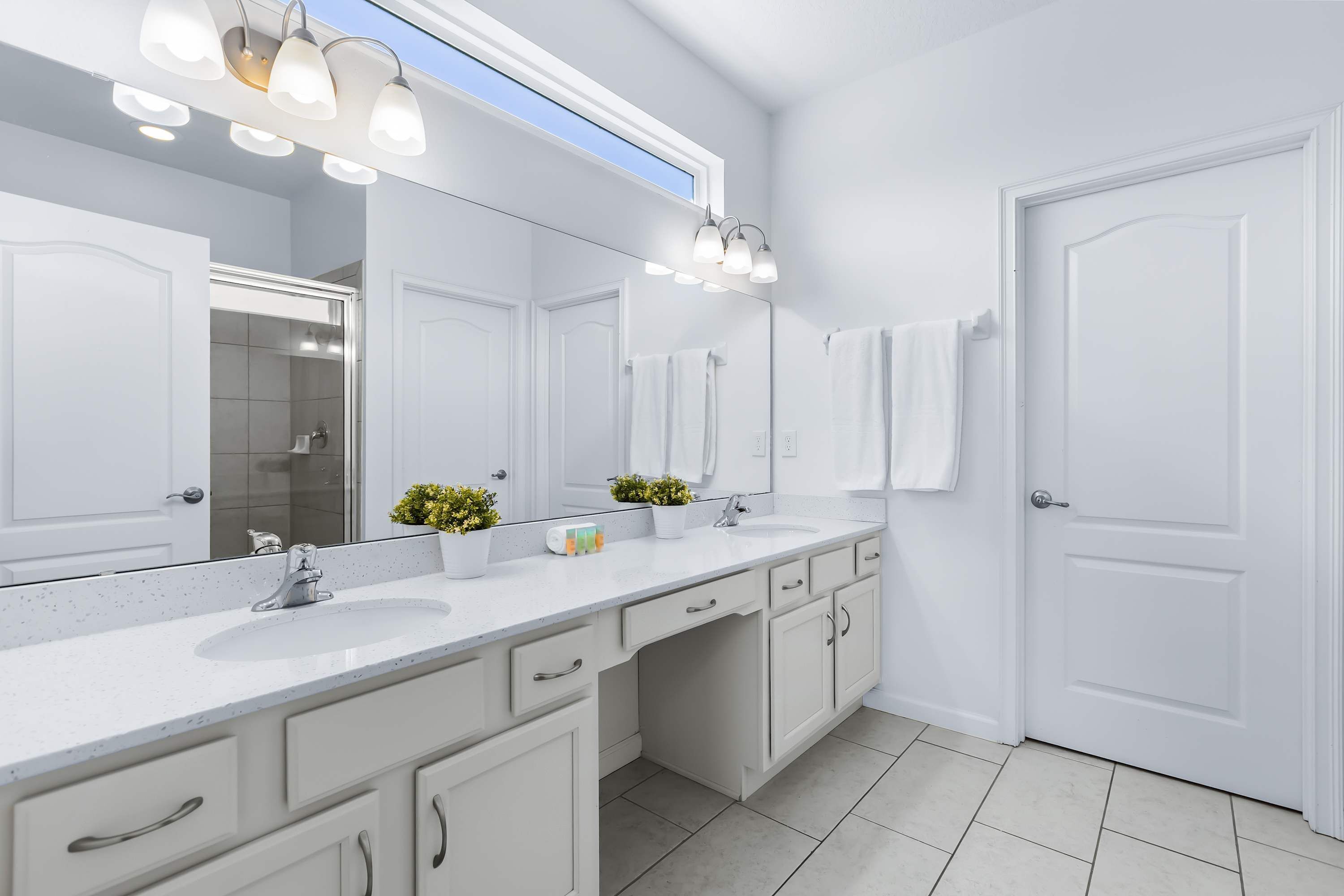 Une salle de bain moderne avec un grand miroir, un meuble-lavabo blanc et un espace douche.