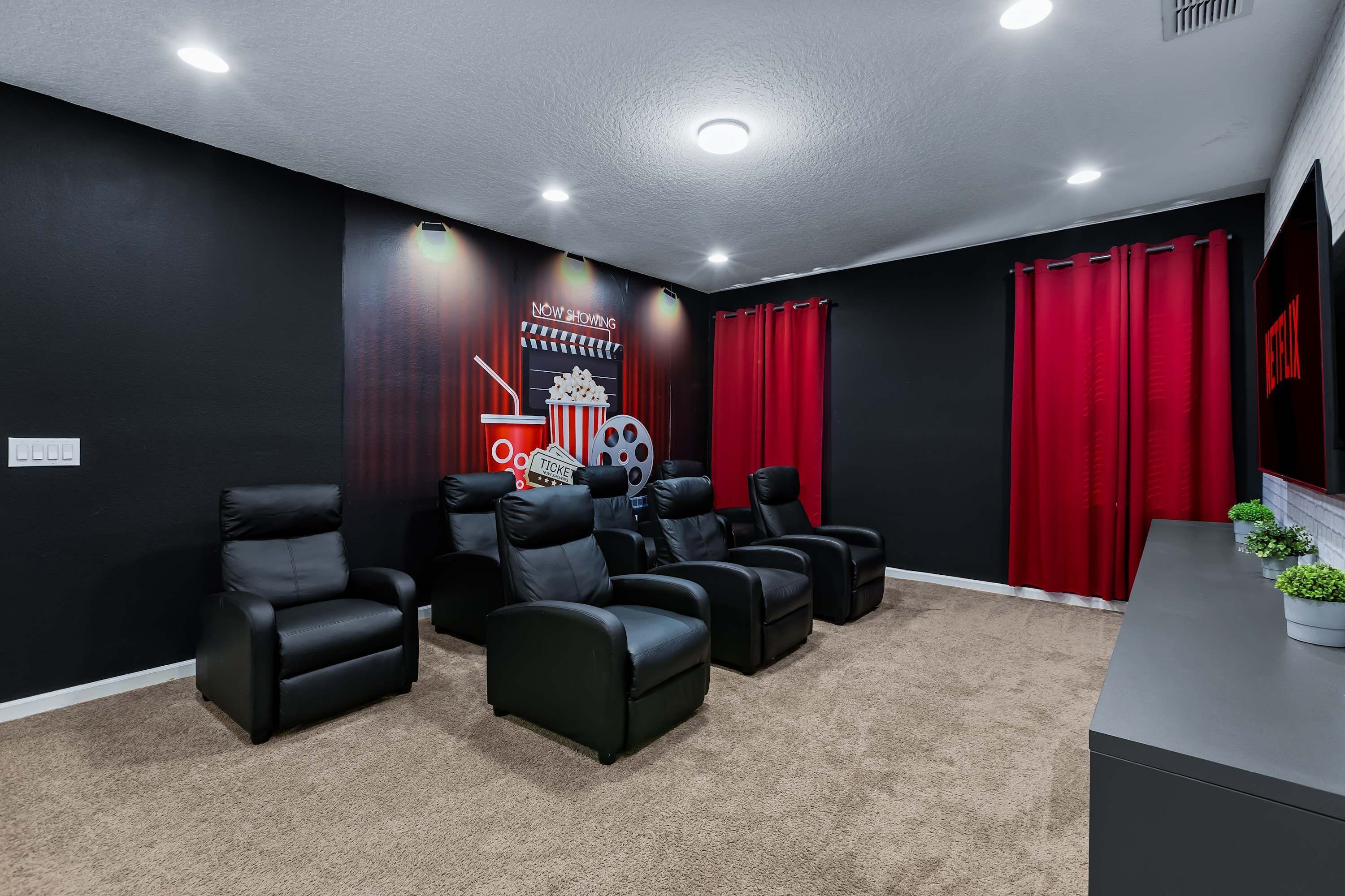 Une pièce aux murs noirs, aux rideaux rouges et aux nombreux fauteuils en cuir noir disposés pour permettre aux spectateurs de s’asseoir.