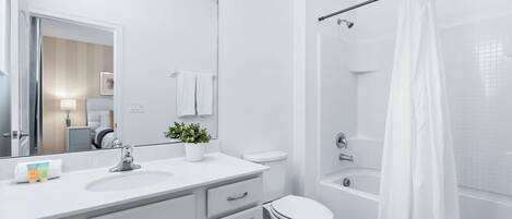 A modern bathroom with a white sink, toilet, and bathtub.