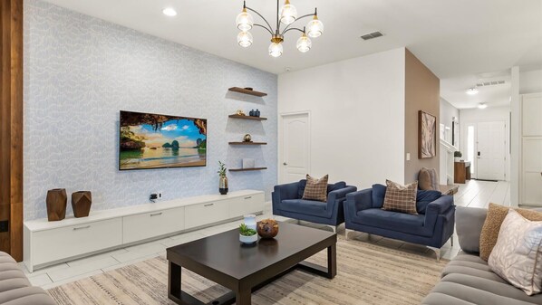 A modern living room with a large flat-screen TV, two sofas, a coffee table, and decorative shelves. - Upstay Solterra Resort Villa w Pool Games Room (Davenport)
