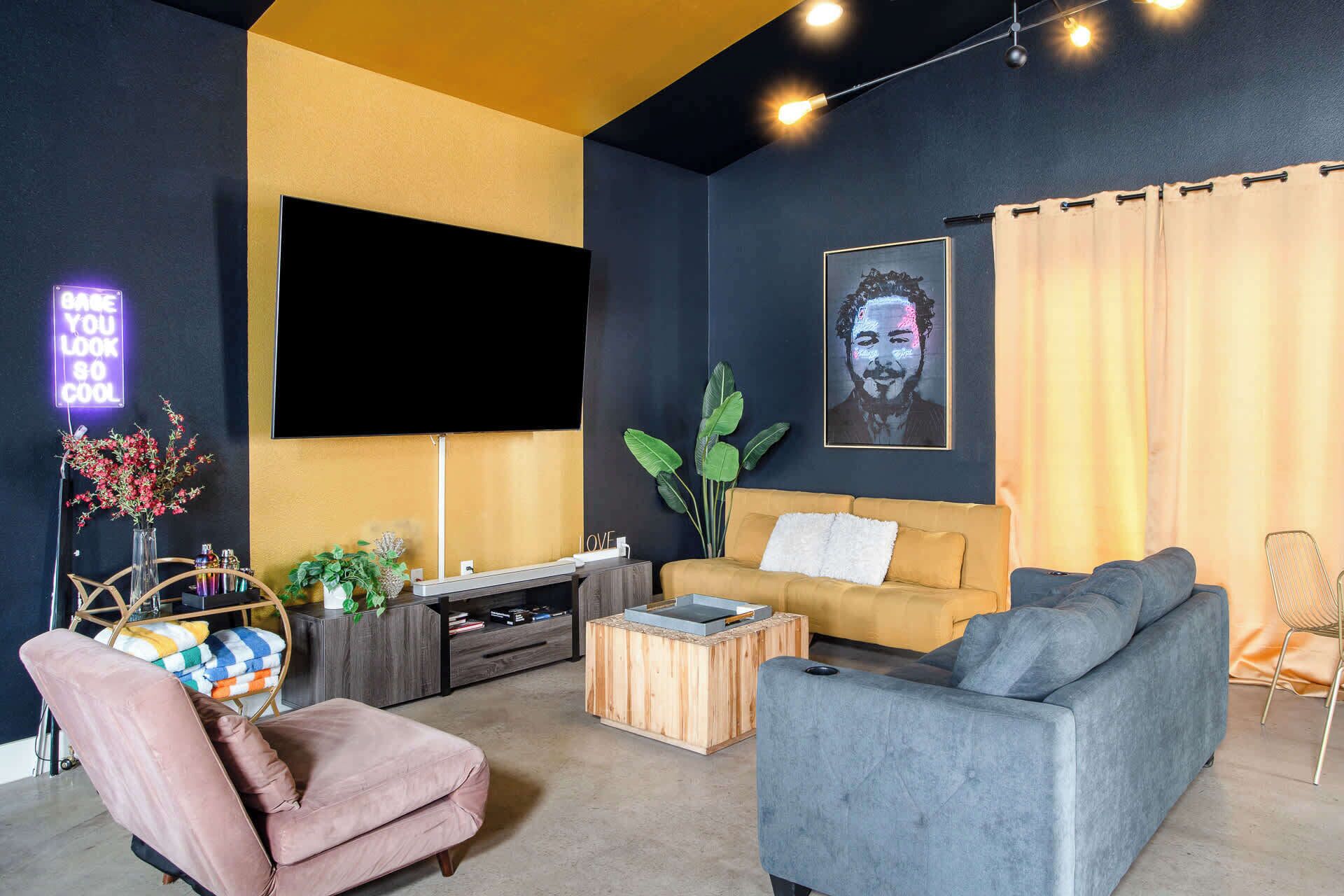 A modern living room with a sofa, a coffee table, a TV mounted on the wall, and a plant.