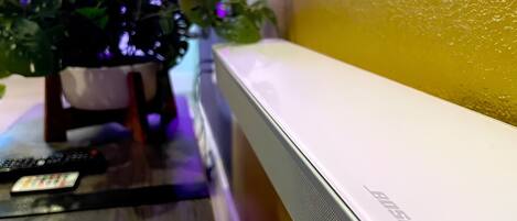 Un téléviseur à écran plat posé sur une surface en bois, avec une télécommande et un magazine à proximité.