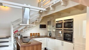 Une cuisine moderne avec des meubles blancs, des appareils en acier inoxydable et un îlot central en bois.