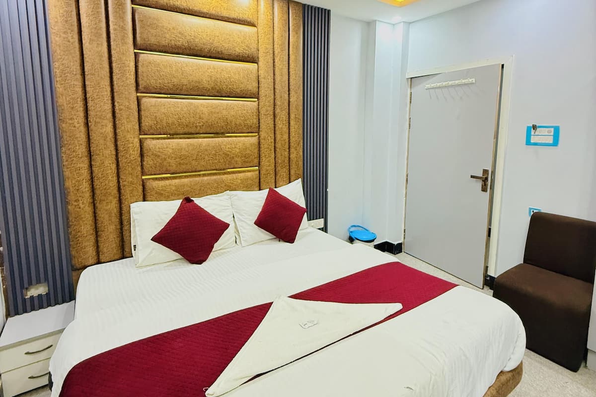 A hotel room with a large bed, a ceiling fan, a door with a sign, and a brown chair.