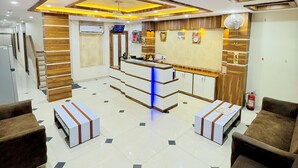 A reception area with a counter, seating, and a fire extinguisher. - Hotel Manish International (Varanasi)