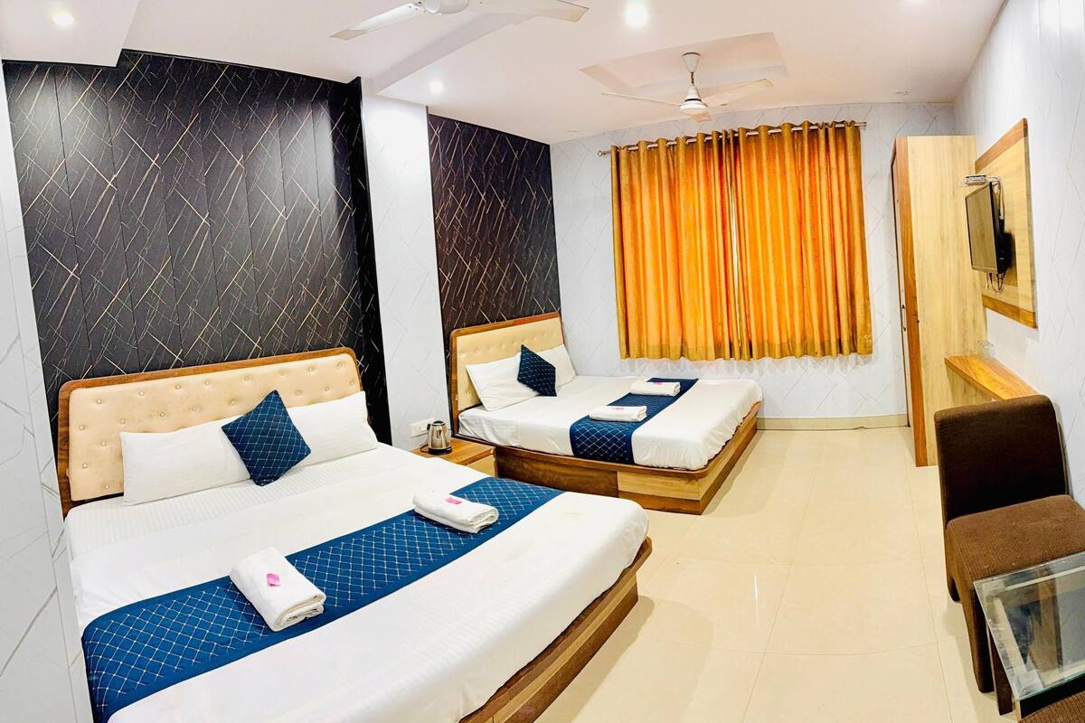 A hotel room with two beds, a TV, a glass table, and a chair.