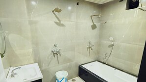 A modern bathroom with a sink, toilet, bathtub, and shower. - Hotel Manish International (Varanasi)