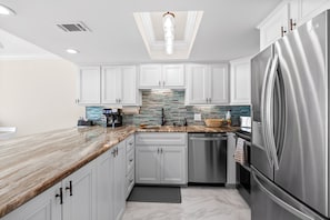 A modern kitchen with white cabinets, a stainless steel refrigerator, and a skylight. - Oceanfront-Waterpointe 1 Unit 702-Windy Hill Beach-Sleeps 6-3br/2ba-Pools (North Myrtle Beach)