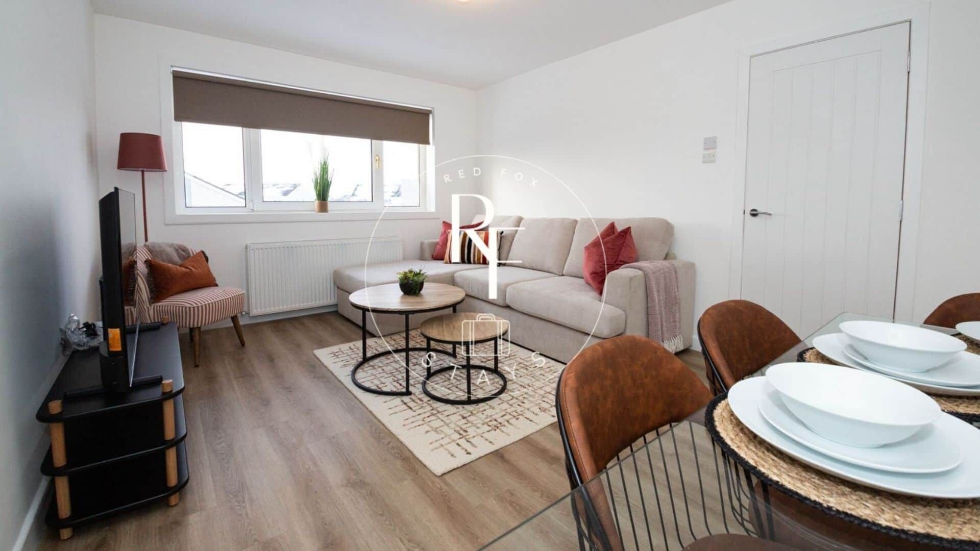 A modern living room with a sofa, a coffee table, and a dining area with chairs and plates.