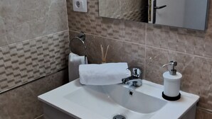Ein modernes Badezimmer mit Waschbecken, Spiegel und Schrank in Weiß.