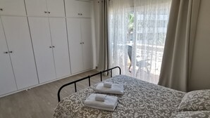 Ein Schlafzimmer mit Bett, Kleiderschrank und Blick ins Freie.