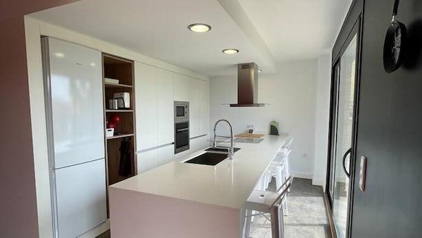 Una cocina moderna con armarios blancos, una isla grande y electrodomésticos integrados.