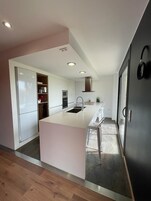 Una cocina moderna con armarios blancos, una isla grande y electrodomésticos integrados.