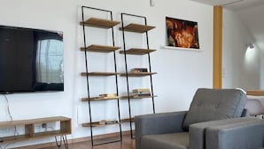 Una sala de estar moderna con una mesa de centro de madera, sofás grises, un televisor negro y una alta estantería negra.