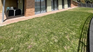 Una casa moderna de dos pisos con techo plano, ventanas amplias y un balcón.