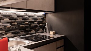 A modern kitchen with a black and white backsplash, stainless steel appliances, and a red kettle.