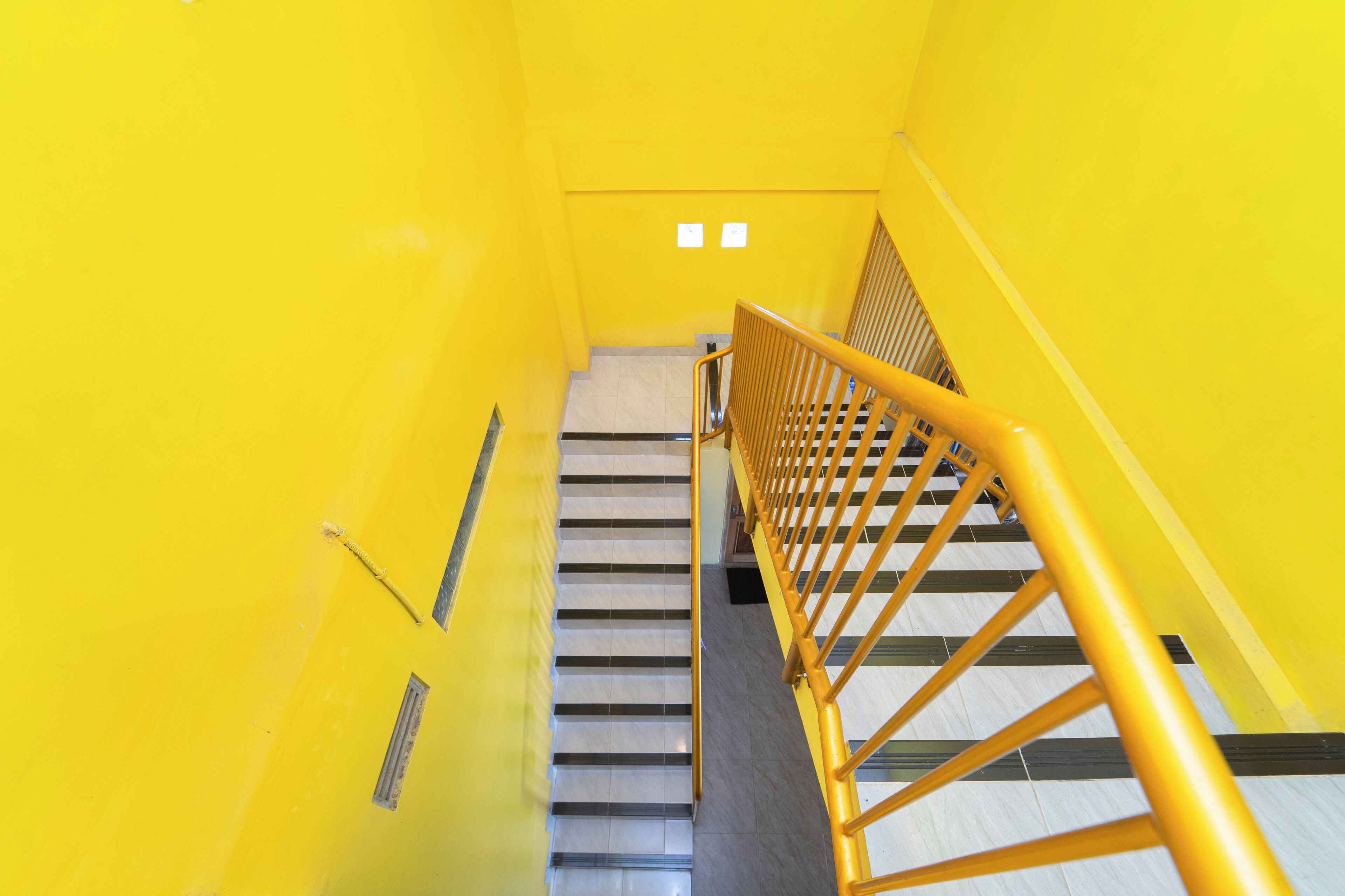 A staircase with yellow walls and a wooden handrail.