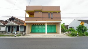 Un edificio de dos pisos con una puerta de garaje verde, un toldo amarillo y un letrero que indica una curva adelante.
