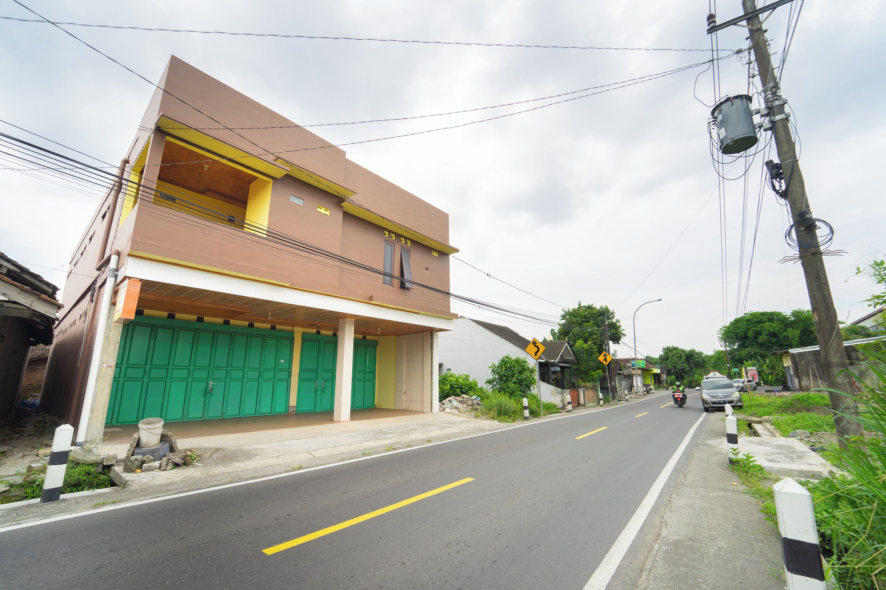 Un edificio de dos pisos con una puerta verde y un toldo amarillo.