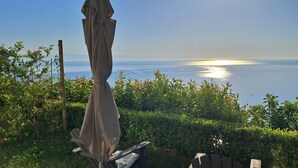 Une terrasse avec une chaise et un parasol, donnant sur une étendue d’eau.