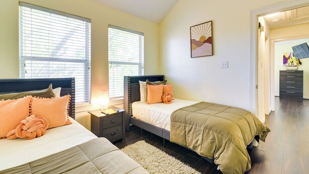 Une chambre avec deux lits, une table de chevet et une commode.