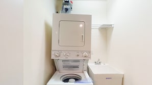Un lavadero pequeño y blanco con lavadora y secadora apiladas.
