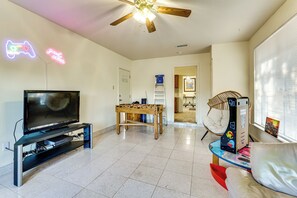 A living room with a TV, foosball table, and a ceiling fan. - Family Home w/ Games & Fenced Yard in San Antonio! (San Antonio)