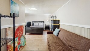 Ein gemütliches Schlafzimmer mit Bett, braunem Sofa, Schreibtisch und einer Regalwand.