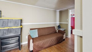 Ein gemütlicher Wohnraum mit einem braunen Sofa, einem kleinen Tisch mit Ventilator und einem Stauraum mit Schubladen und Regalen.
