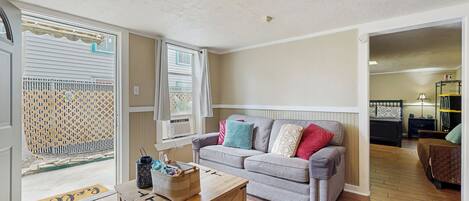 A living room with a grey sofa, wooden coffee table, and a patterned rug.