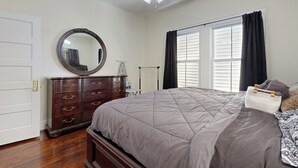 A bedroom with a large bed, a dresser, a mirror, a ceiling fan, and a window with curtains. - 2-story Galveston Getaway w/ Balcony & Patio (Galveston)