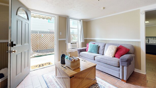 A living room with a grey sofa, a wooden coffee table, and a door leading to a balcony. - 2-story Galveston Getaway w/ Balcony & Patio (Galveston)