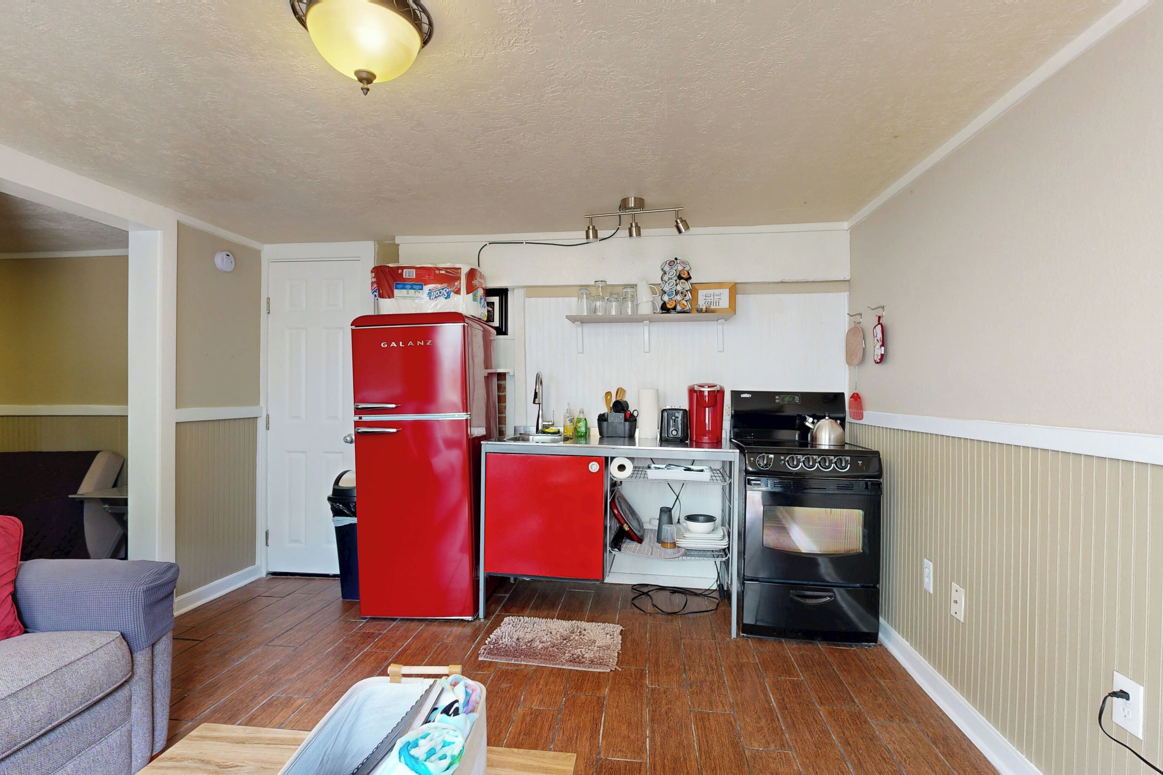 A compact kitchen with a red refrigerator, a stove, and a small countertop.