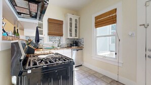 A kitchen with a black stove, white cabinets, and a window with a blind. - 2-story Galveston Getaway w/ Balcony & Patio (Galveston)