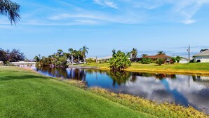 A residential area with a pond, houses, and greenery. - 4BR Home w/ Outdoor Patio & In-ground Pool (Rotonda West)