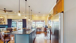 A modern kitchen with a central island, stainless steel appliances, and a dining area with bar stools. - 4BR Home w/ Outdoor Patio & In-ground Pool (Rotonda West)