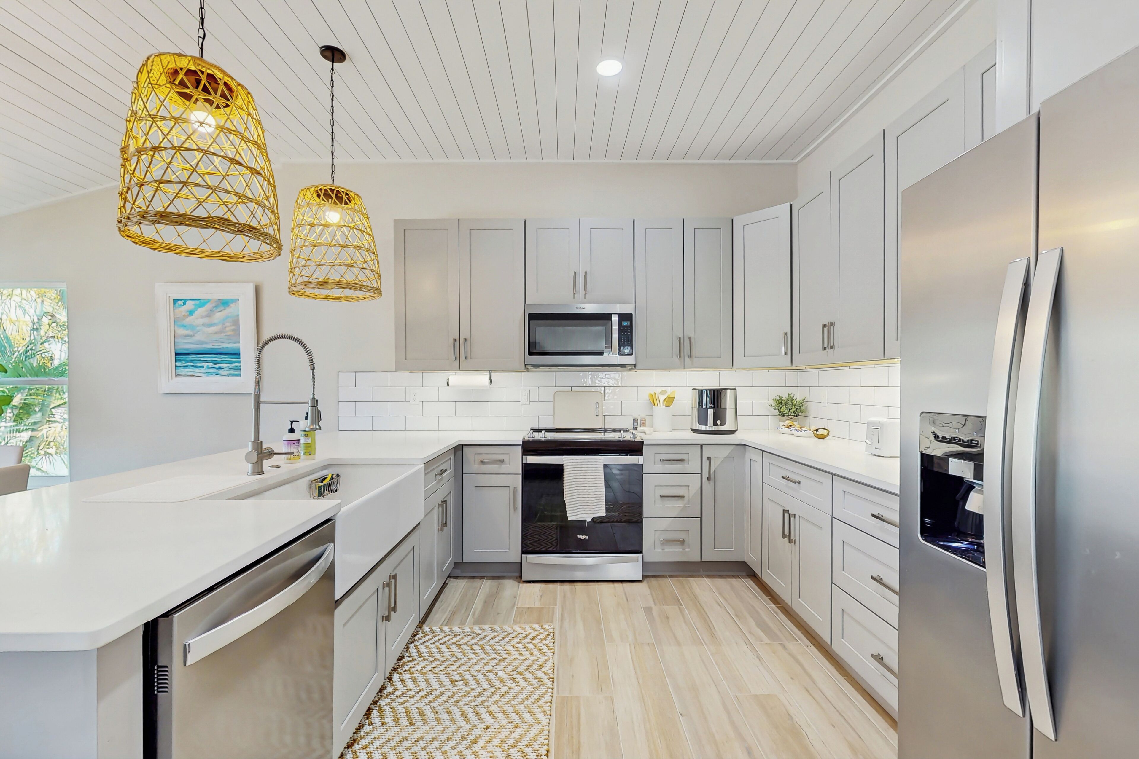A modern kitchen with white cabinetry, stainless steel appliances, and a central island.