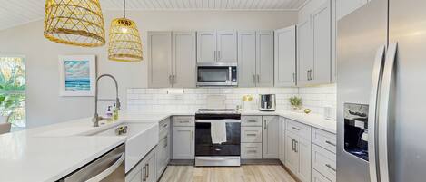A modern kitchen with white cabinetry, stainless steel appliances, and a central island.