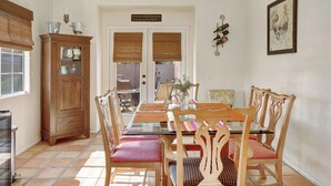 A dining area with a wooden cabinet, a glass-top table, and matching chairs. - 3 BR Home, Private Pool, Close to Event Venues (La Quinta)