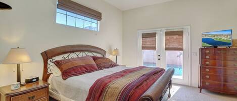 A bedroom with a bed, bedside tables, a dresser, a ceiling fan, and a window with blinds.