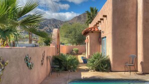 A pool area with a clear view of mountains, surrounded by a stucco building with a tiled roof and a blue door. - 3 BR Home, Private Pool, Close to Event Venues (La Quinta)
