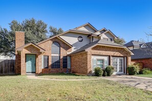A two-story house with a brick facade, a front porch, and a garage. - 9 Mi to Rangers & Cowboys Home Games: DFW Studio (Grand Prairie)