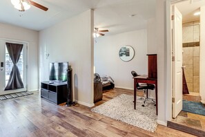 A room with hardwood flooring, a ceiling fan, a bed, a desk, and a television. - 9 Mi to Rangers & Cowboys Home Games: DFW Studio (Grand Prairie)