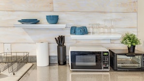 A kitchen with a microwave, toaster, and shelves with bowls and cups. - 9 Mi to Rangers & Cowboys Home Games: DFW Studio (Grand Prairie)
