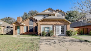 A two-story house with a brick facade, a front porch, and a garage. - 9 Mi to Rangers & Cowboys Home Games: DFW Studio (Grand Prairie)